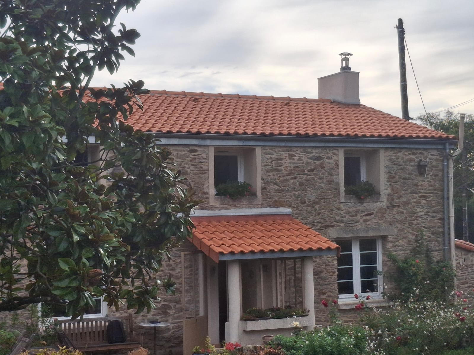Maison en pierre rénovée avec une toiture en tuiles rouges réalisée par OTBE à Carquefou.