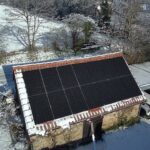 Vue aérienne de panneaux photovoltaïques installés sur une toiture en pierre, production d’électricité en hiver malgré la neige en Loire-Atlantique.