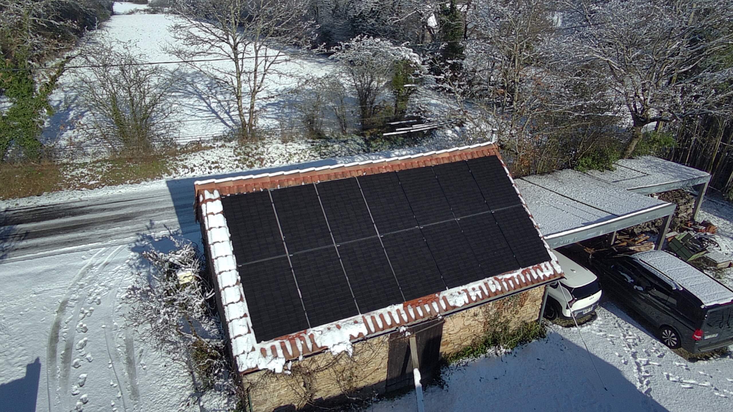 Vue aérienne de panneaux photovoltaïques installés sur une toiture en pierre, production d’électricité en hiver malgré la neige en Loire-Atlantique.